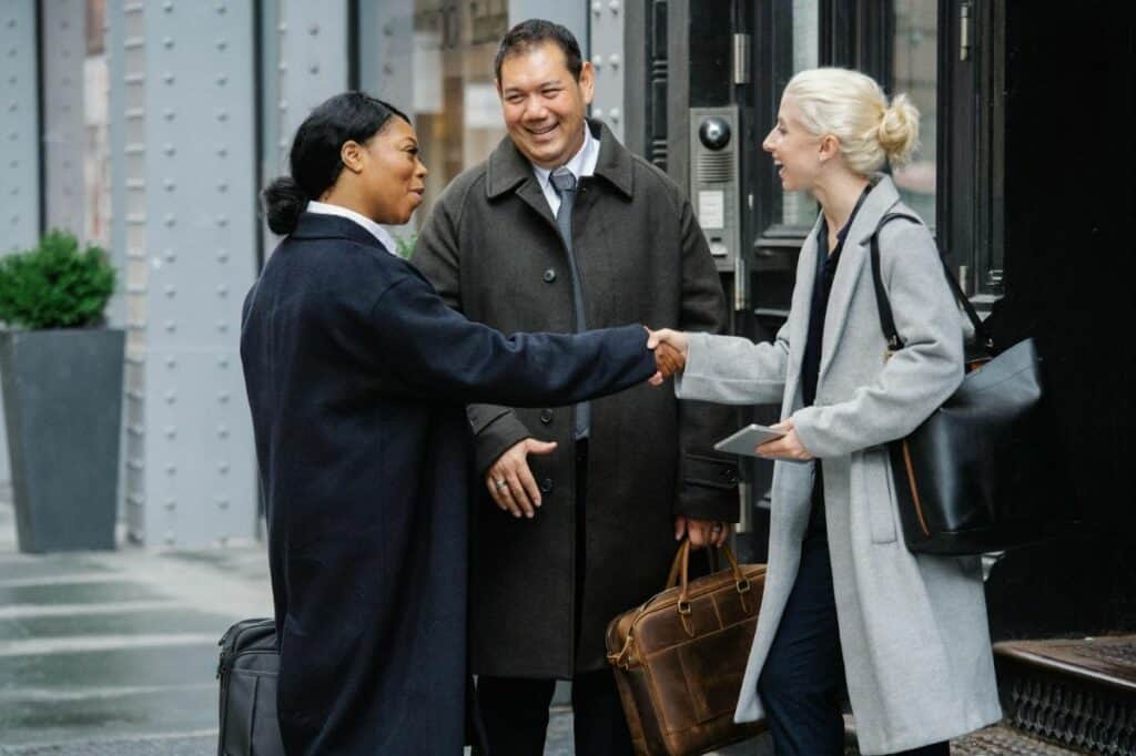 Three diverse professionals greeting each other with handshakes