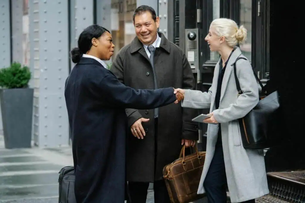 Three diverse professionals greeting each other with handshakes