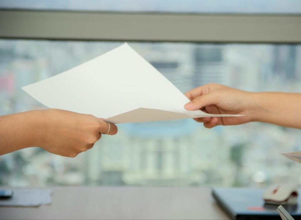 Hands passing document with blurred cityscape behind