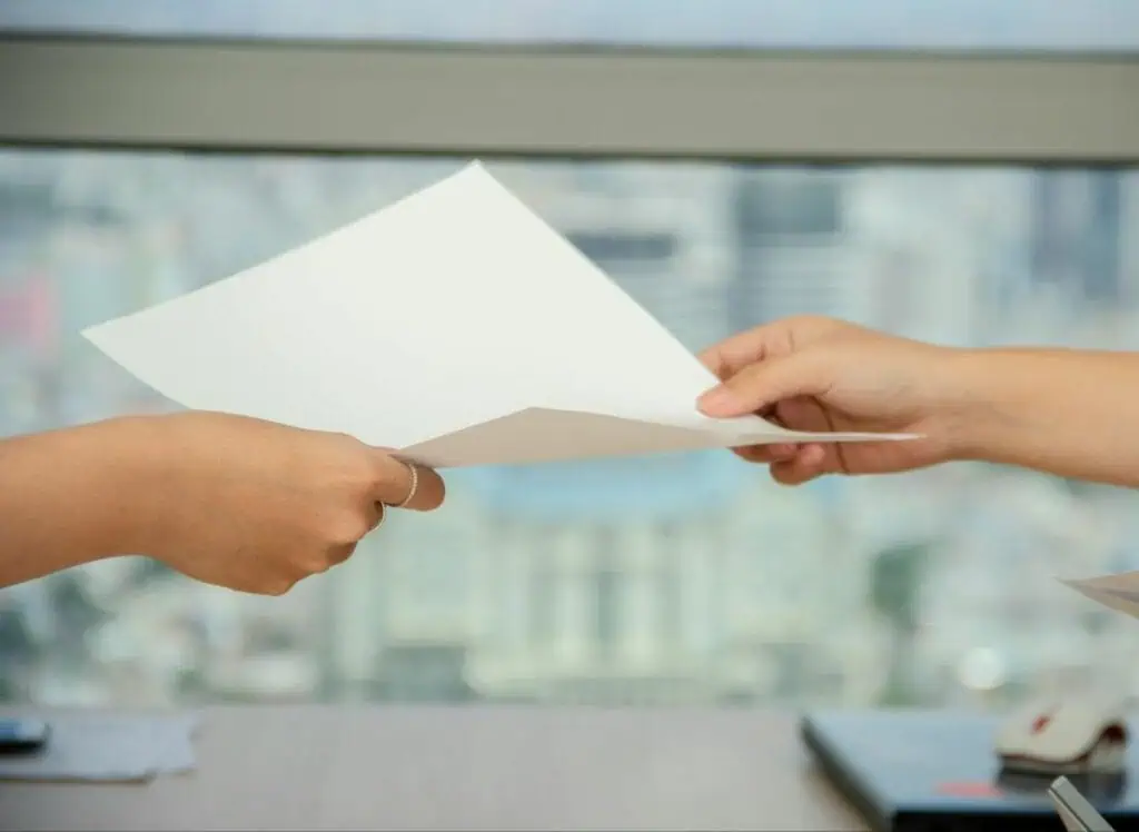 Hands passing document with blurred cityscape behind