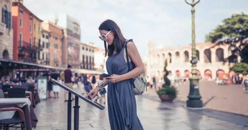 Woman in blue dress using audio guide device in a bustling Italian plaza