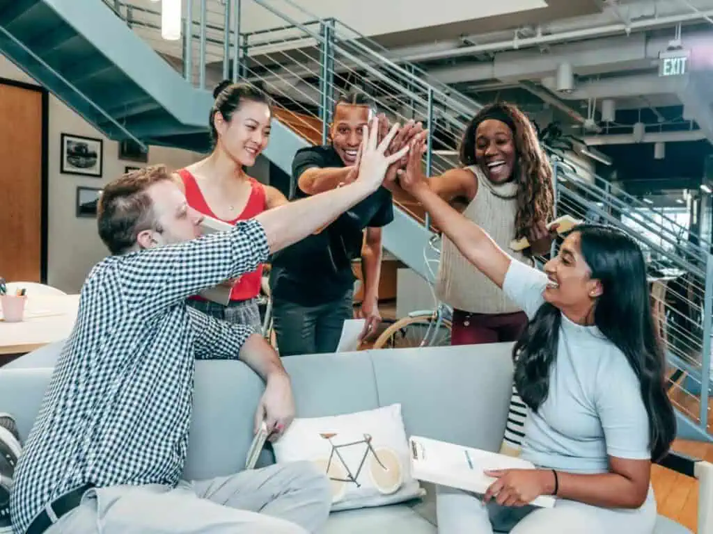 Group of diverse coworkers giving a high five in an office setting