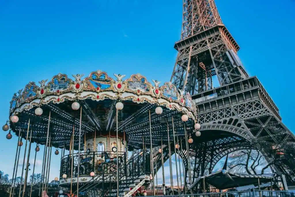 Ornate carousel in front of the Eiffel Tower against a blue sky