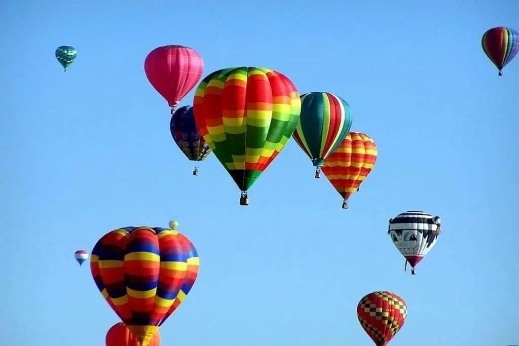 Multiple brightly colored hot air balloons floating in a clear blue sky