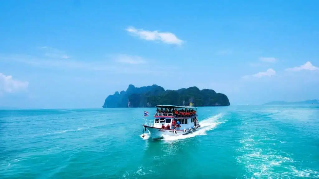Tourist boat sailing towards tropical island in turquoise waters